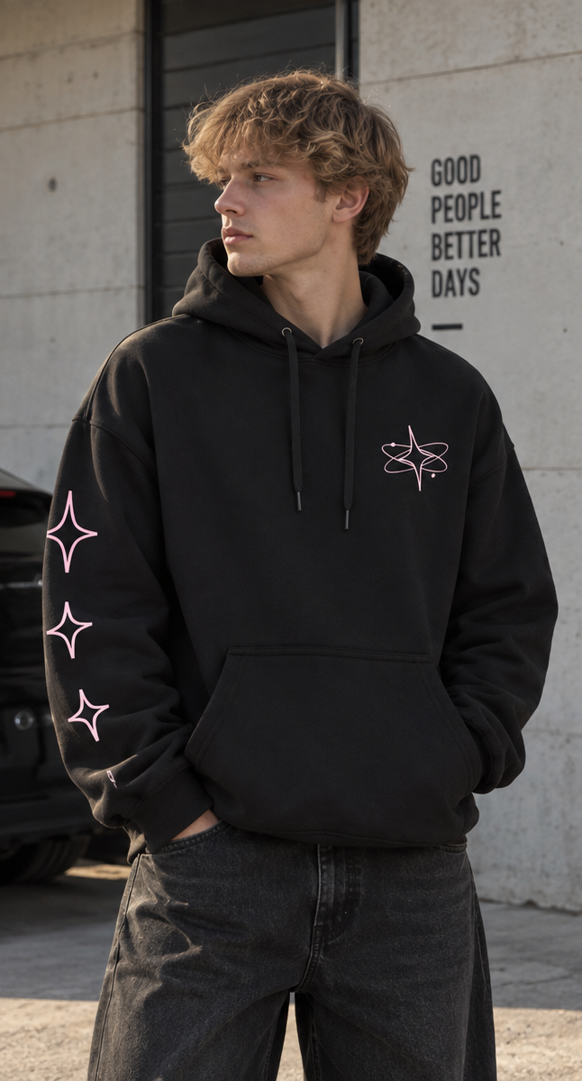 Sweat noir à capuche ORBITE vu de face, avec petit motif orbital rose clair sur la poitrine et trois étoiles sur la manche droite.