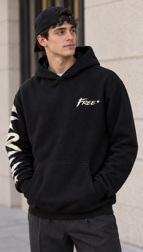 Sweat noir à capuche FREE vu de face, avec petit lettrage clair et étoile sur la poitrine, motif sur la manche droite et poche kangourou.