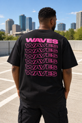 T-shirt oversize WAVES noir vu de dos, avec typographie rose fuchsia répétée en cascade.